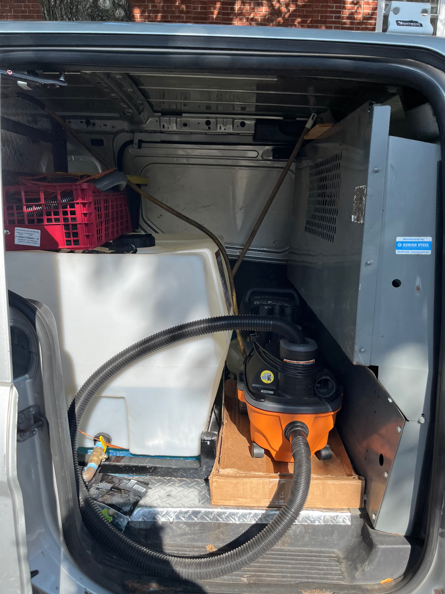 Inside the van: water tank plumbed to a hose and a wet/dry extractor vacuum
